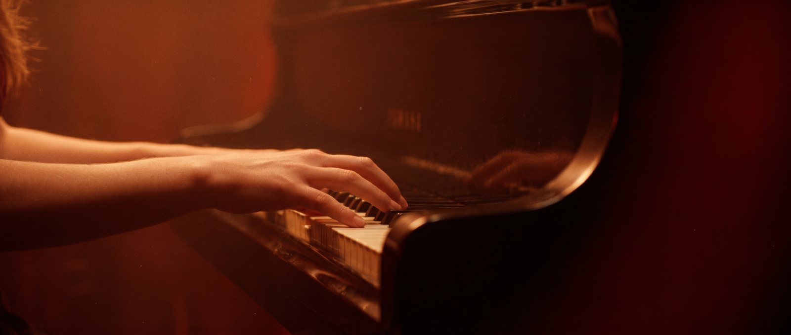 a pianist's hands resting on the keys of a grand piano